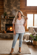 Plus size woman wearing white striped v-neck casual tee in a cozy cabin setting