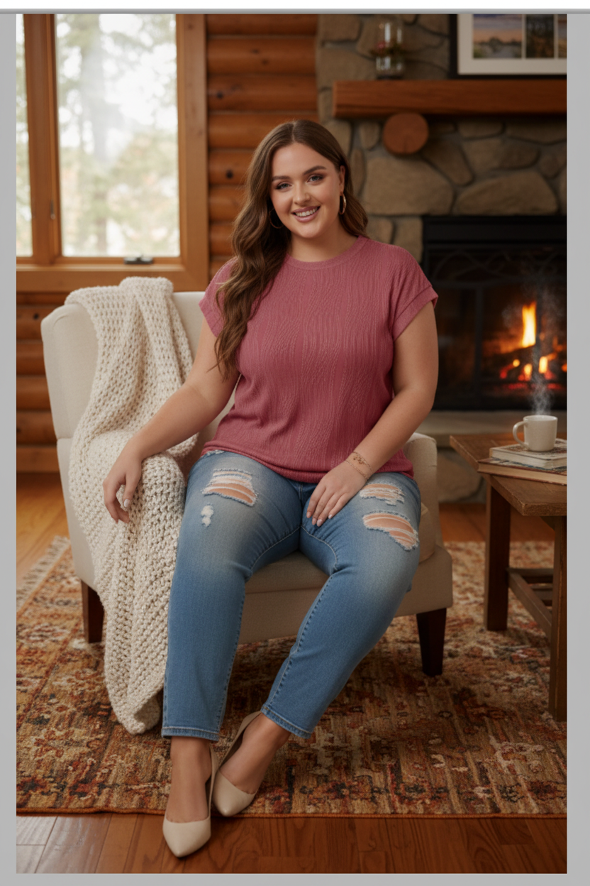 Plus size woman wearing dusty rose wavy textured cap sleeve tee in a cozy cabin setting